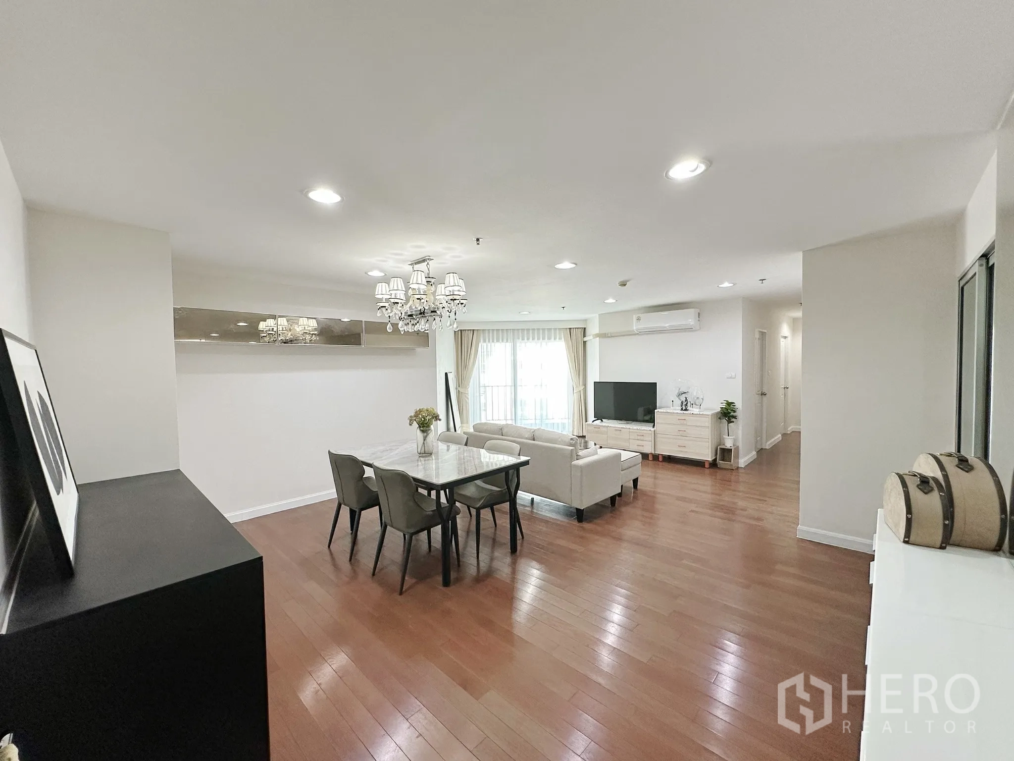 คอนโด for sale in Huai Khwang, Bangkok - โถงนั่งเล่นและทานอาหารแบบโอเพ่นสเปซ มีแชนเดอเลียร์ โซฟา ทีวี ประตูกระจกสู่ระเบียง และพื้นไม้.