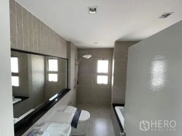 独立式住宅 出售在Bueng Kum, Bangkok - 宽敞浴室，米色瓷砖，大镜面，步入式淋浴与浴缸。