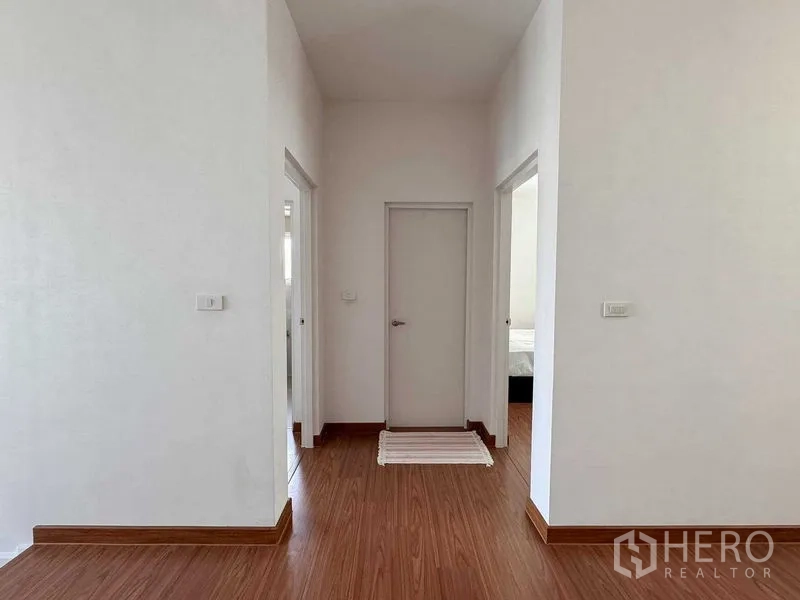 บ้าน ให้เช่าหรือขายในBang Khen, Bangkok - โถงชั้นบนผนังสีขาว พื้นลายไม้ และประตู 3 บาน