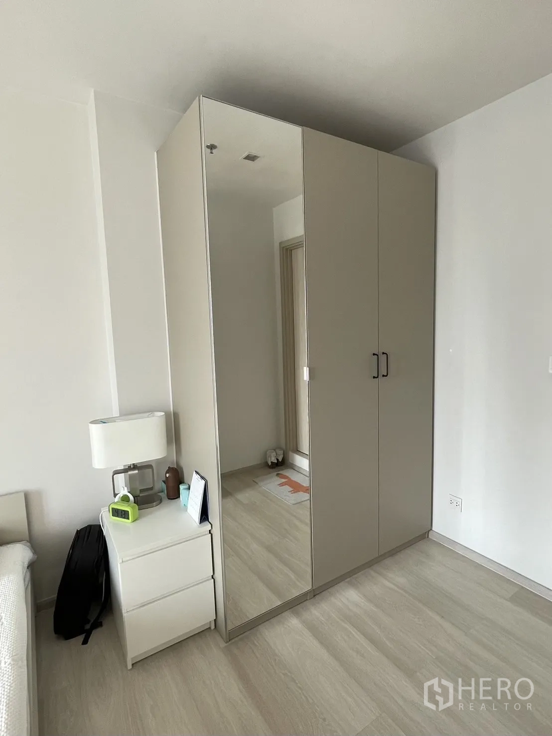 Condominium for rent in Pathum Wan, Bangkok - Bedroom corner showing mirrored wardrobe and bedside table on light wood flooring.