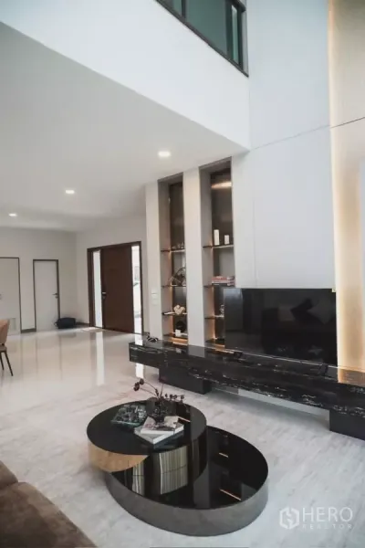 Detached House for rent in Bang Phli, Samut Prakan - Open-plan living with double-volume ceiling, floating TV unit and round nesting coffee tables.