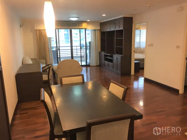 Condominium for rent in Watthana, Bangkok - Open-plan living and dining room with wooden floors, built-in media wall and balcony access.