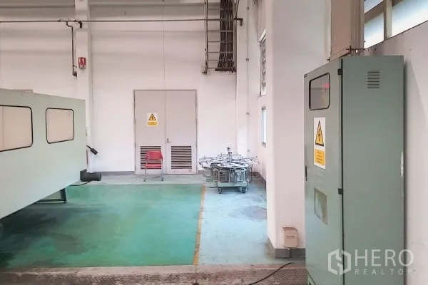 工厂 出售在Rayong - 车间一隅，电控柜、警示标识与绿色环氧地坪。