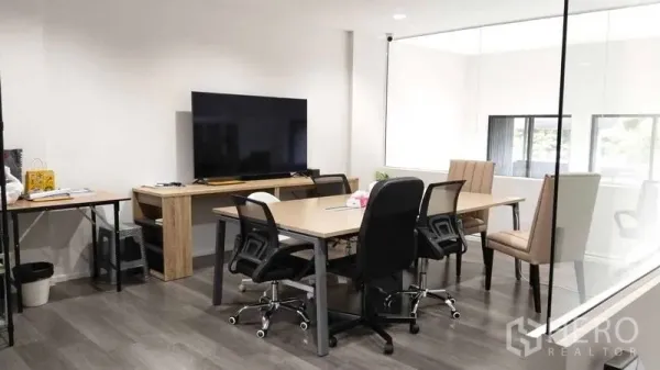 Home Office for rent - Modern meeting area behind a clear glass wall with shared table and chairs.