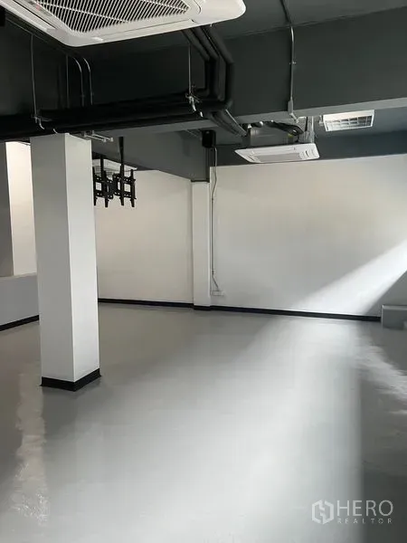 零售空间 出租在Watthana, Bangkok - 空置店铺明亮角落，环氧地坪与外露管线。