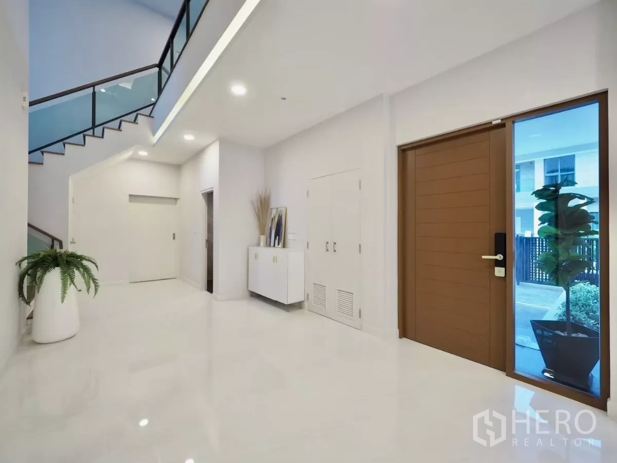Detached House for rent in Bang Phli, Samut Prakan - Spacious entry hall with wood front door, glossy floors and glass stair railing.