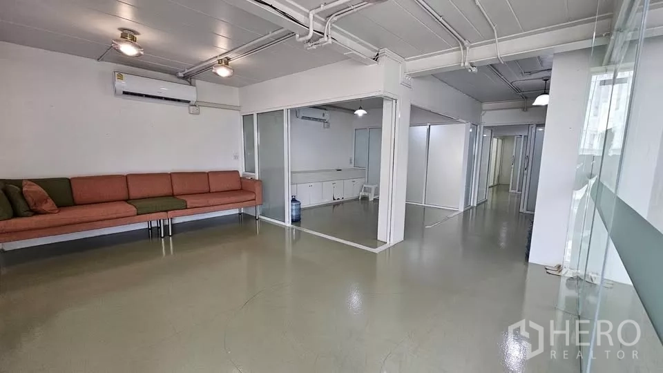 零售空间 出租在Watthana, Bangkok - 开放式零售楼层，玻璃隔间、长沙发、空调与外露天花管线。