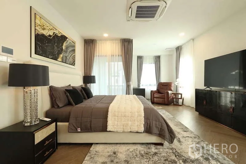 บ้าน ให้เช่าในSaphan Sung, Bangkok - มุมมองห้องนอนมาสเตอร์ไปยังผนังทีวี พร้อมเก้าอี้เอนหลังข้างหน้าต่าง