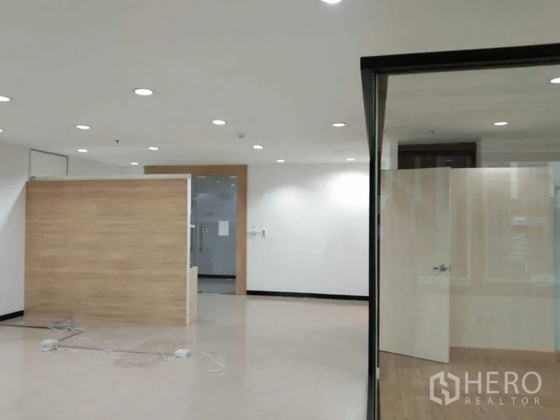 Office Space for rent in Watthana, Bangkok - Reception view showing wood accent wall, glass entry door, and corner of the glass meeting room.