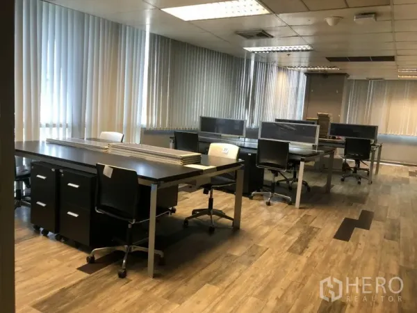 Office Space for rent in Khlong Toei, Bangkok - Open‑plan office with multiple workstations, wood floors, vertical blinds and fluorescent ceiling lights.