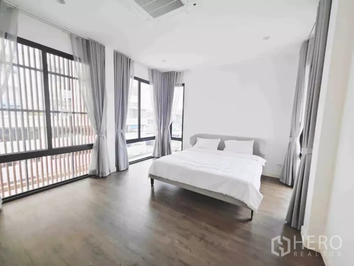 独立式住宅 出租在Phaya Thai, Bangkok - 采光充足卧室，转角落地窗、灰帘与深木地。