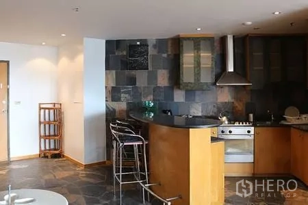 Condominium for rent in Ratchathewi, Bangkok - Open-plan kitchen with slate tile backsplash, breakfast bar, stools and stainless appliances.