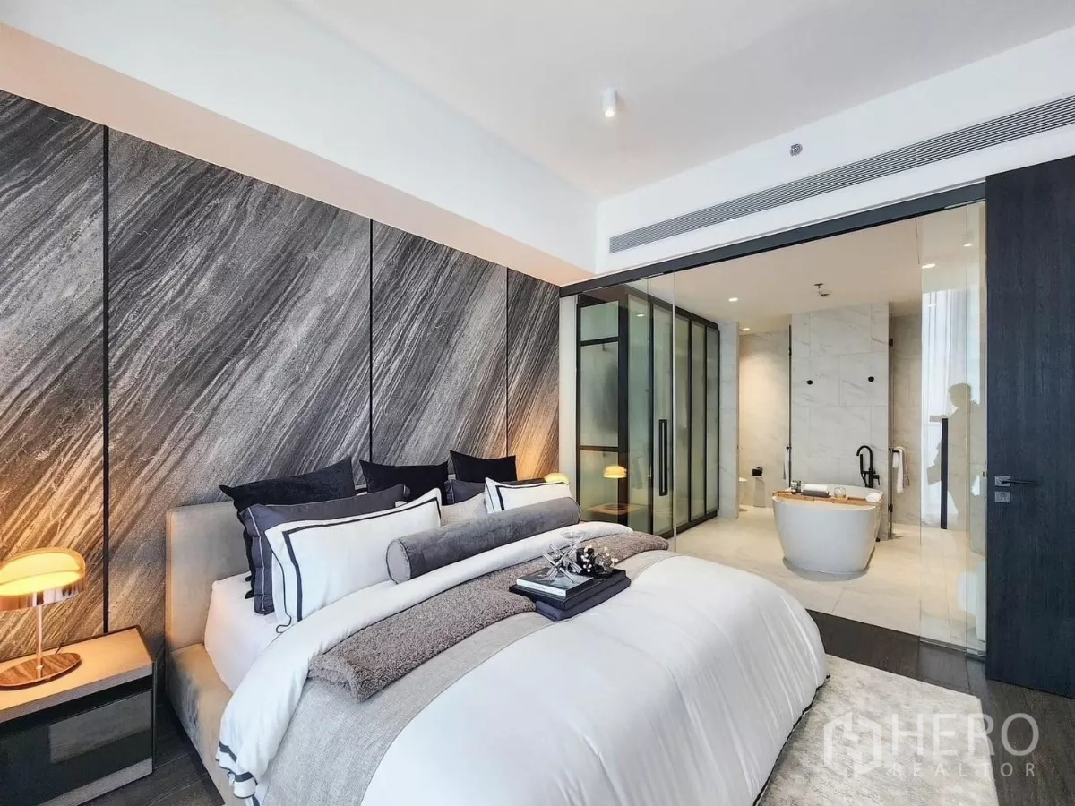 公寓 出租在Bang Rak, Bangkok - 主卧带石纹背景墙，玻璃隔断连接带浴缸的套内卫浴。