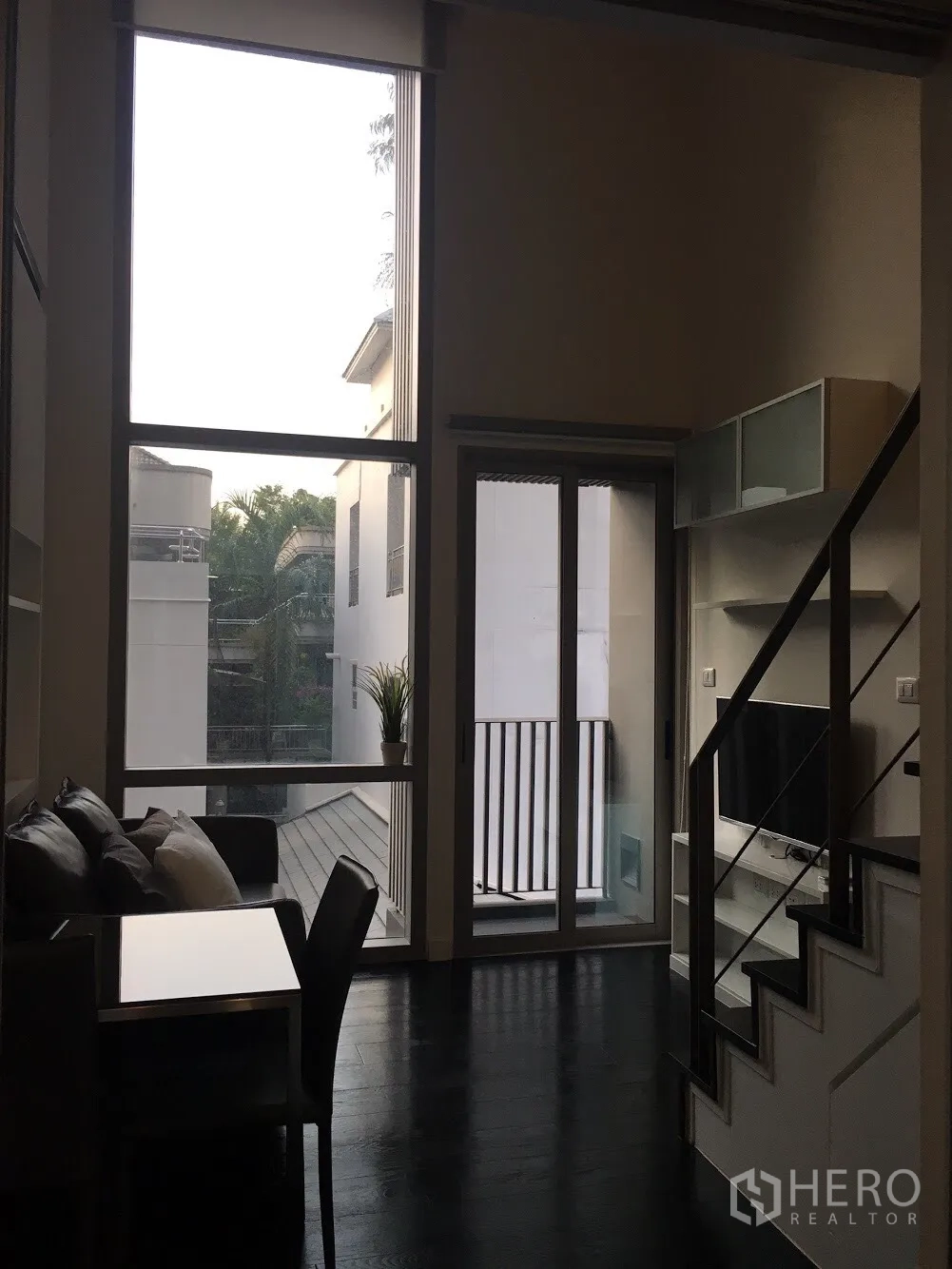 คอนโด ให้เช่าในKhlong Toei, Bangkok - ห้องนั่งเล่นเพดานสูง หน้าต่างเต็มผนัง ประตูระเบียง บันได และชั้นวางทีวี