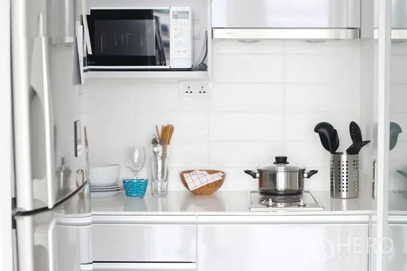 公寓 出售在Phra Khanong, Bangkok - 白色紧凑厨房，带冰箱、微波炉、灶台与厨具。