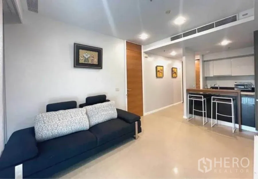 คอนโด ให้เช่าในKhlong San, Bangkok - ห้องนั่งเล่นแบบเปิดโล่ง โซฟาสีเข้ม ข้างครัวพร้อมบาร์ท็อป