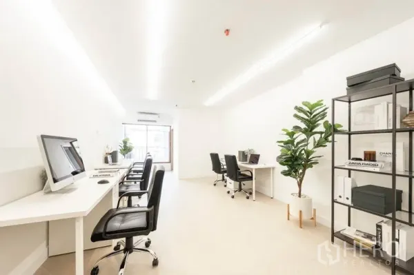 Office Space for rent in Khlong Toei, Bangkok - Light-filled office corridor with multiple workstations, computers, indoor plants and a large window at the end.