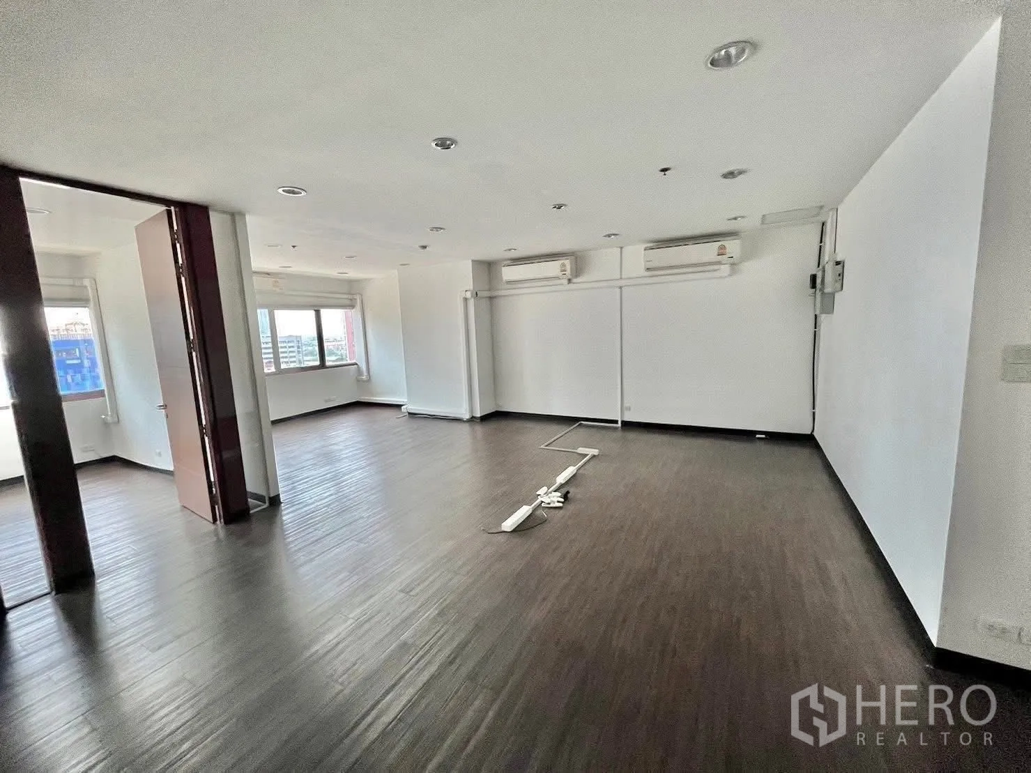 ออฟฟิศ for rent in Watthana, Bangkok - พื้นที่สำนักงานแบบเปิด พื้นลามิเนตโทนเข้ม ไฟดาวน์ไลท์ และหน้าต่างบานกว้าง.