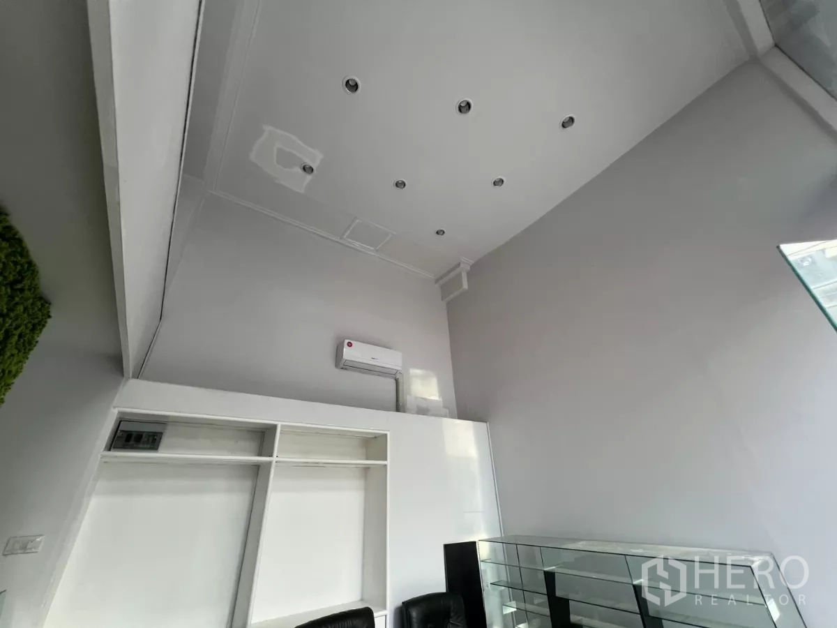 พื้นที่ขายปลีก ให้เช่า - มุมเงยเห็นเพดานสูงสีขาว ไฟดาวน์ไลท์ และเครื่องปรับอากาศ