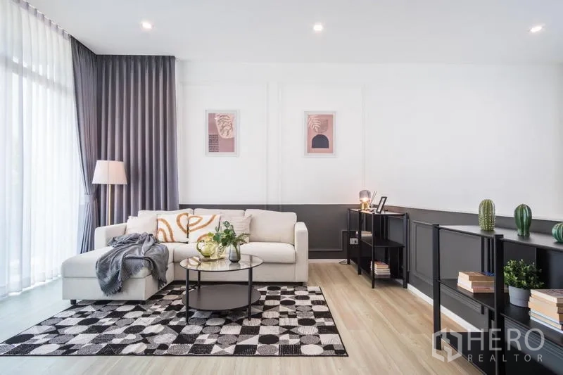 ทาวน์เฮาส์ ให้เช่าหรือขายในSuan Luang, Bangkok - ห้องนั่งเล่นโทนสว่าง โซฟารูปตัวแอล โต๊ะกลางทรงกลม พรมลาย และชั้นวางของ