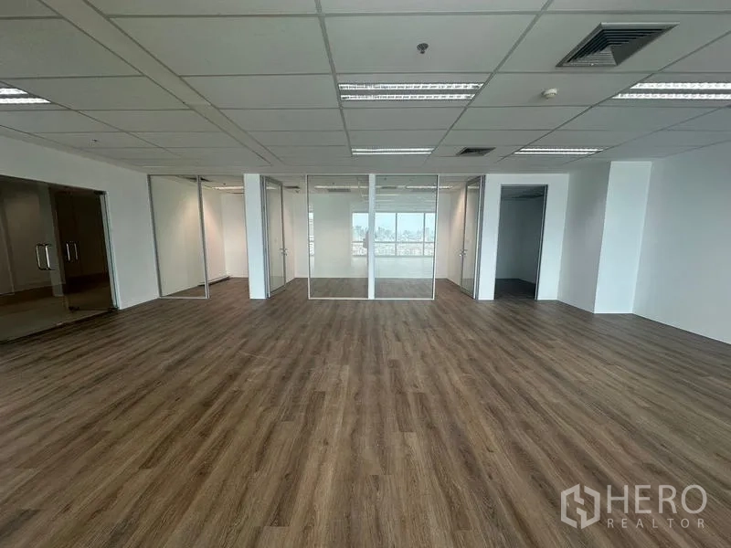 สำนักงาน ให้เช่า - โถงทำงานกว้าง หันหน้าเข้าห้องประชุมผนังกระจก พร้อมไฟเพดานสมัยใหม่.