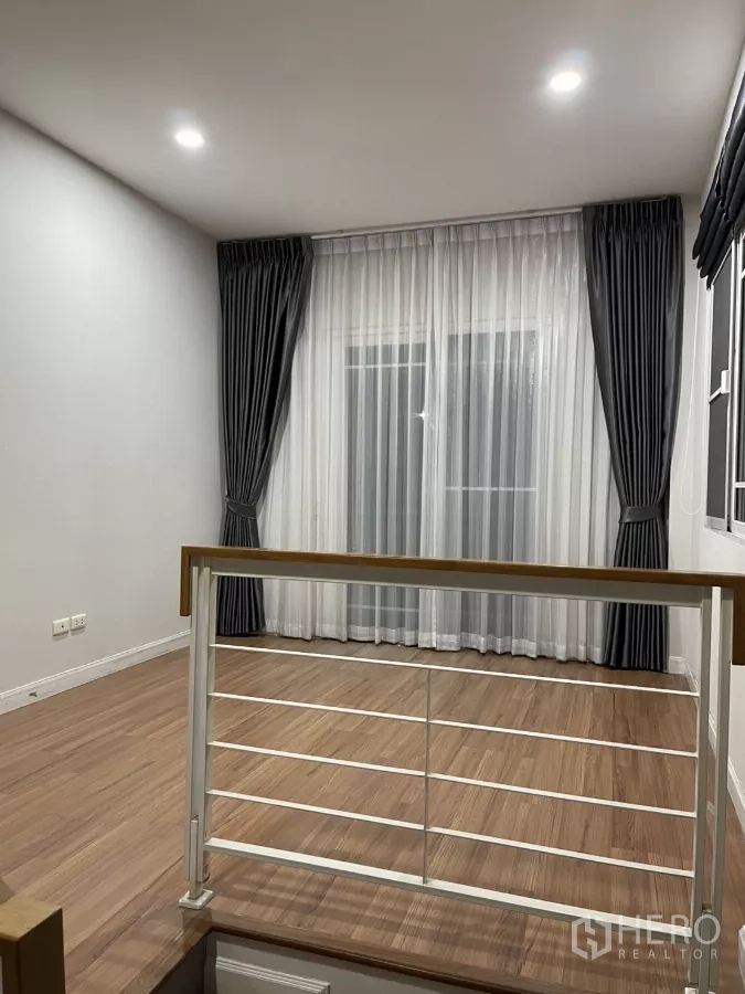 บ้าน ให้เช่าในBang Kapi, Bangkok - โถงพักผ่อนชั้นบน ปูพื้นไม้ ม่านโปร่งหน้าประตูระเบียง