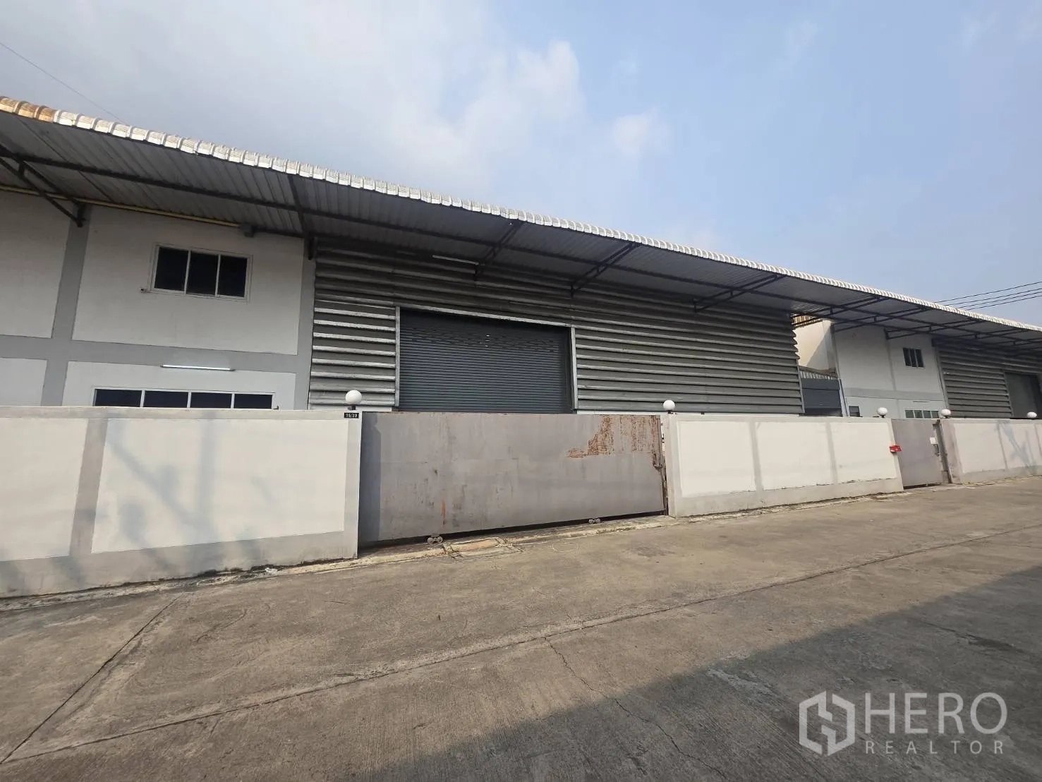 工厂 for rent or sale in Mueang Samut Sakhon, Samut Sakhon - 一排厂房建筑，金属包板外墙、卷闸门与围墙。