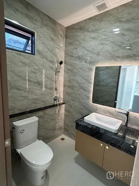 Detached House for rent or sale in Suan Luang, Bangkok - Contemporary bathroom with marble-look tiles, backlit mirror, vanity and toilet