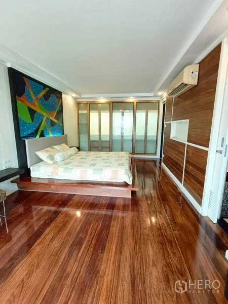 คอนโด ให้เช่าในWatthana, Bangkok - มุมห้องนอนมาสเตอร์ ตู้บิลท์อินบานฝ้ากระจก ผนังลายไม้ และเครื่องปรับอากาศ.