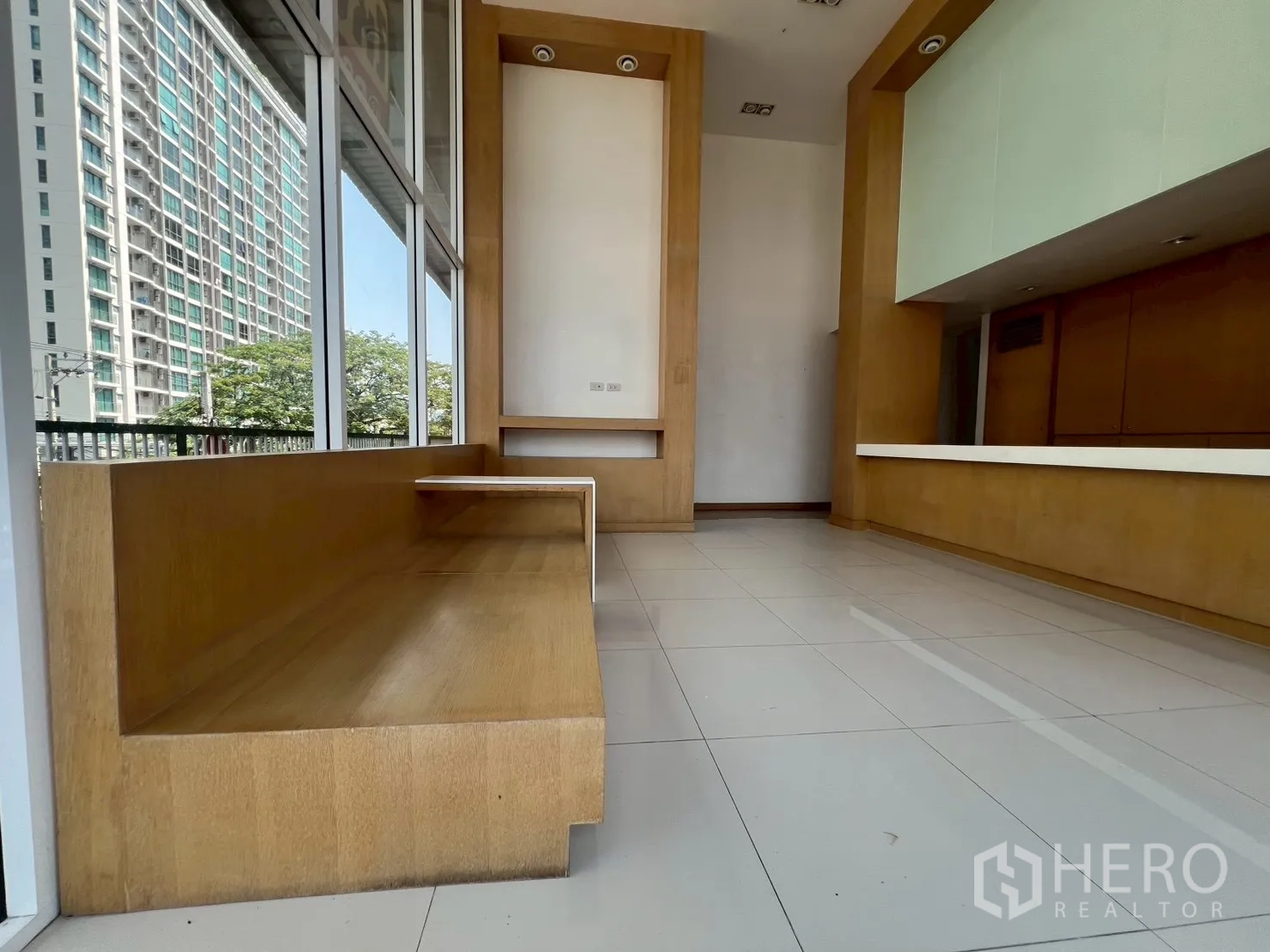 พื้นที่ขายของ for rent in Watthana, Bangkok - ม้านั่งไม้บิวท์อินริมหน้าต่างกระจกสูง มองเห็นวิวเมืองและเคาน์เตอร์ต้อนรับ