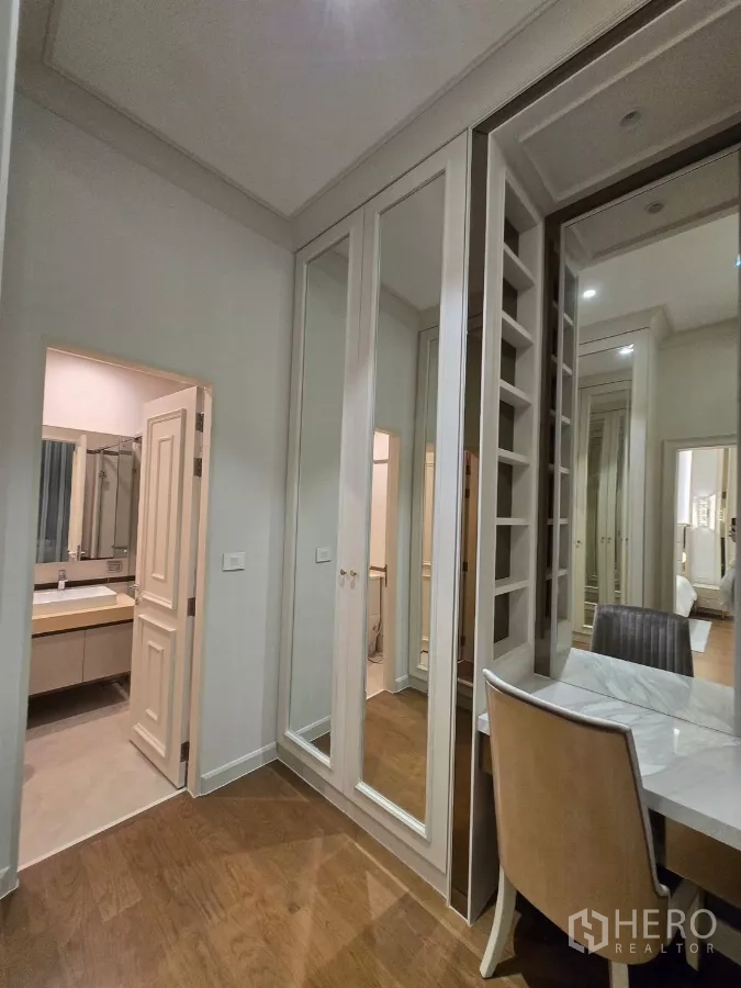 Detached House for rent or sale in Bang Kapi, Bangkok - Dressing area with mirrored cabinetry leading to an ensuite bathroom and study desk.