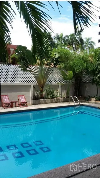 公寓 出租在Khlong Toei, Bangkok - 室外游泳池，周围有棕榈树与日光躺椅。