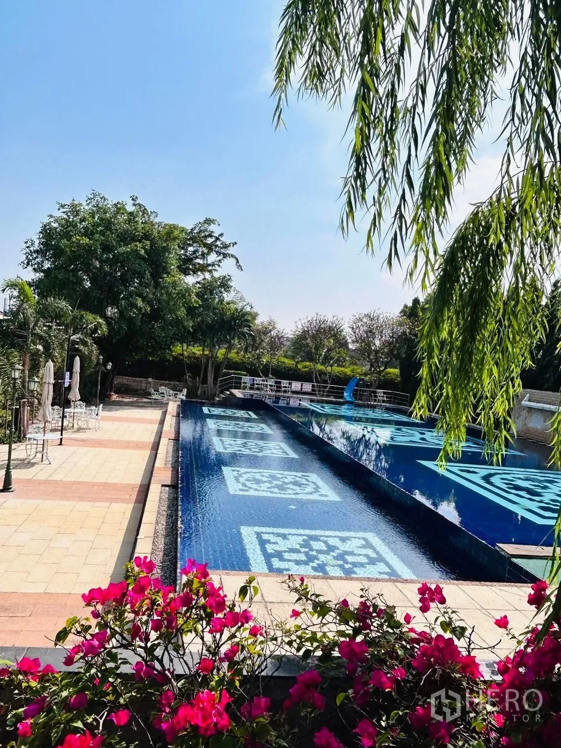 บ้าน ให้เช่าในLat Krabang, Bangkok - สระว่ายน้ำส่วนกลาง กระเบื้องลายสีน้ำเงิน พื้นที่นั่งเล่น และดอกเฟื่องฟ้า