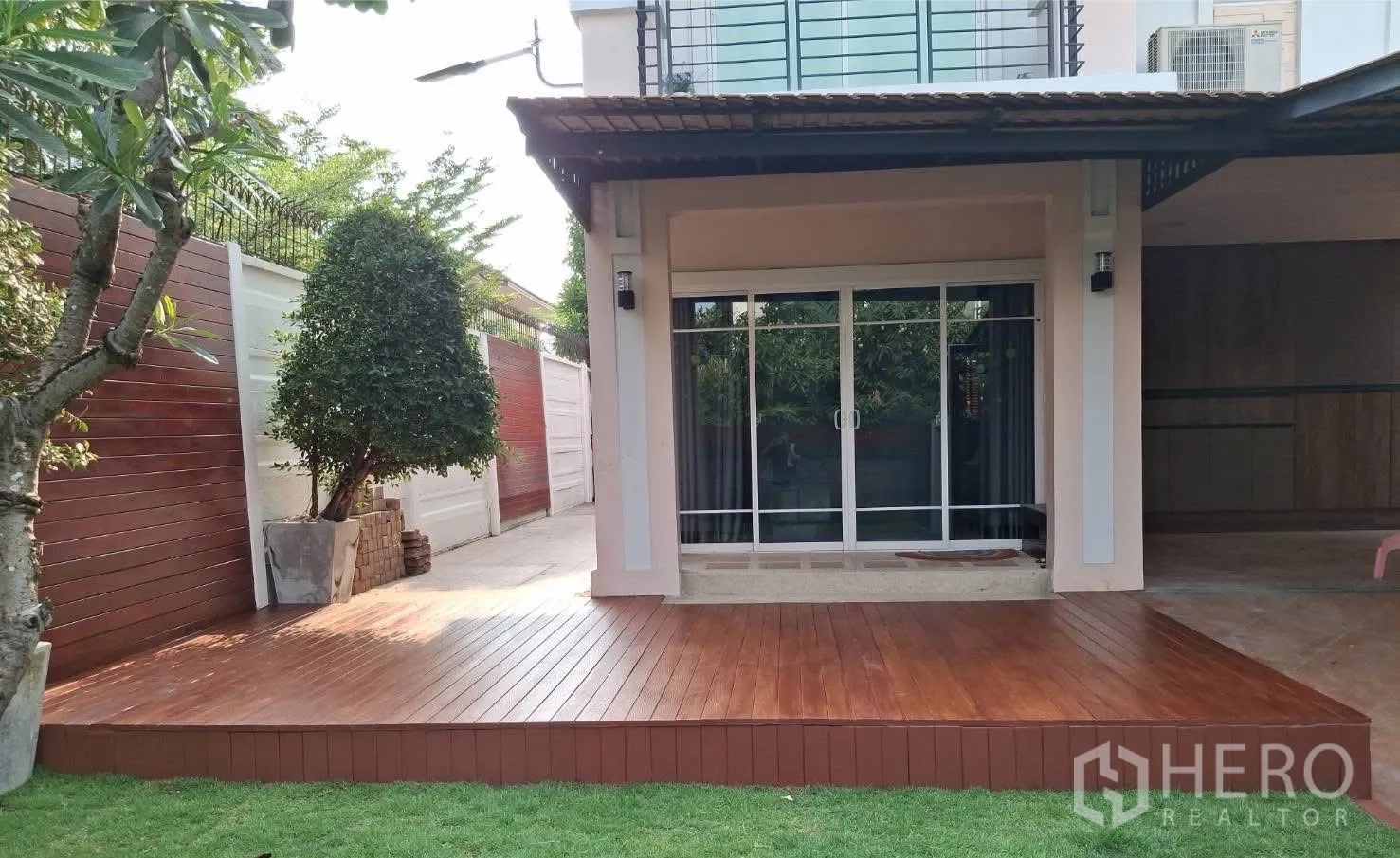 บ้าน ให้เช่า - ระเบียงไม้ยกพื้นด้านหน้าพร้อมประตูบานเลื่อนและที่จอดรถมีหลังคา