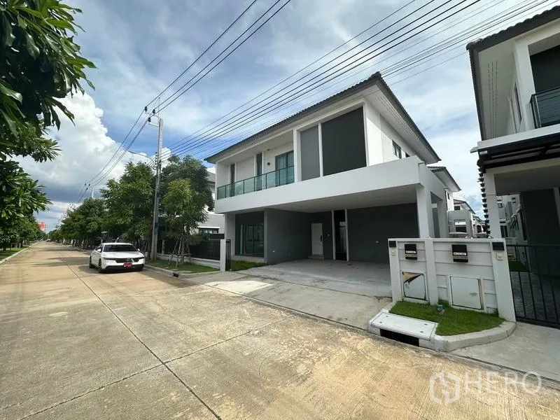 Detached House for sale in Nonthaburi - Street view of the house on a quiet residential road with sidewalks and utilities lines.
