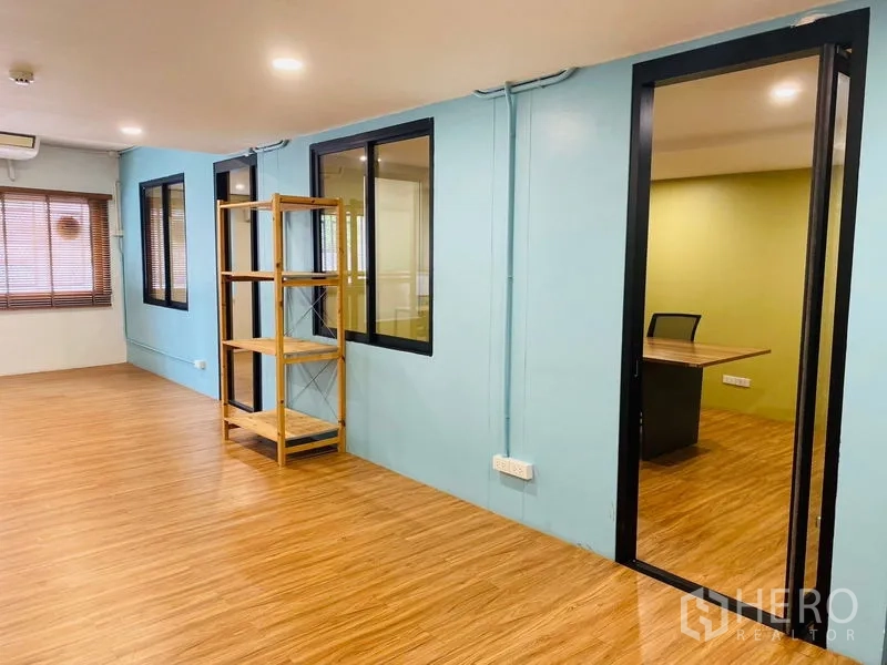 办公空间 出租在Bang Rak, Bangkok - 开放区域，蓝色墙面、置物架与通往会议室的门