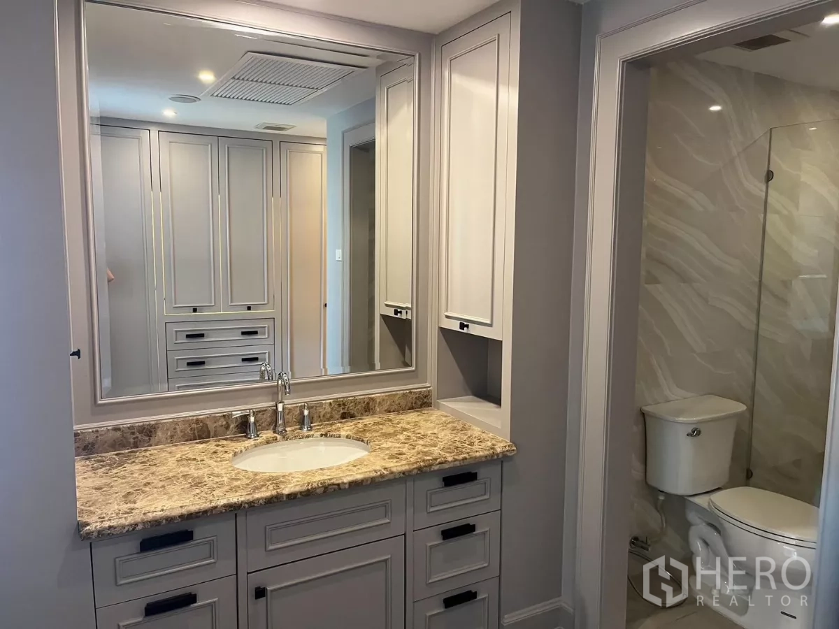 公寓 出租在Pathum Wan, Bangkok - 大镜面洗手台，旁有玻璃淋浴间与坐便器。