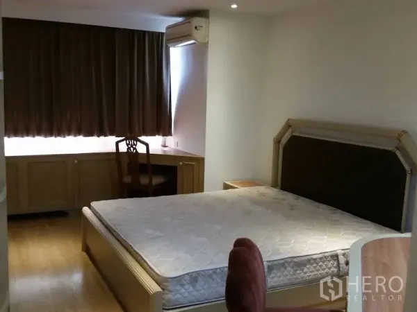 Condominium for rent in Watthana, Bangkok - Master bedroom with large bed, built-in desk by the window, and wall air conditioner.