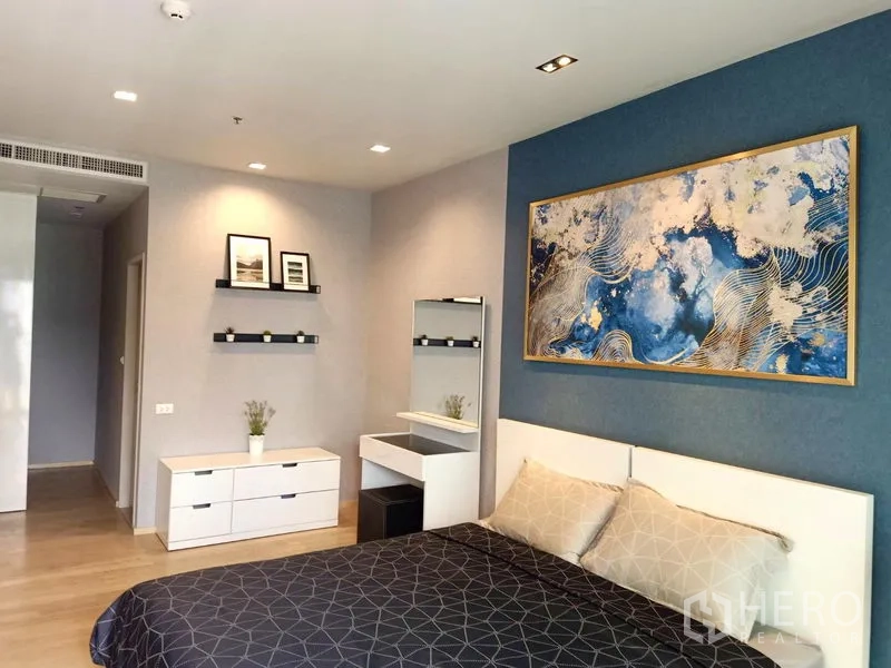 公寓 出租在Bangkok - 静谧卧室，蓝色背景墙，白色床架，梳妆台与置物架。