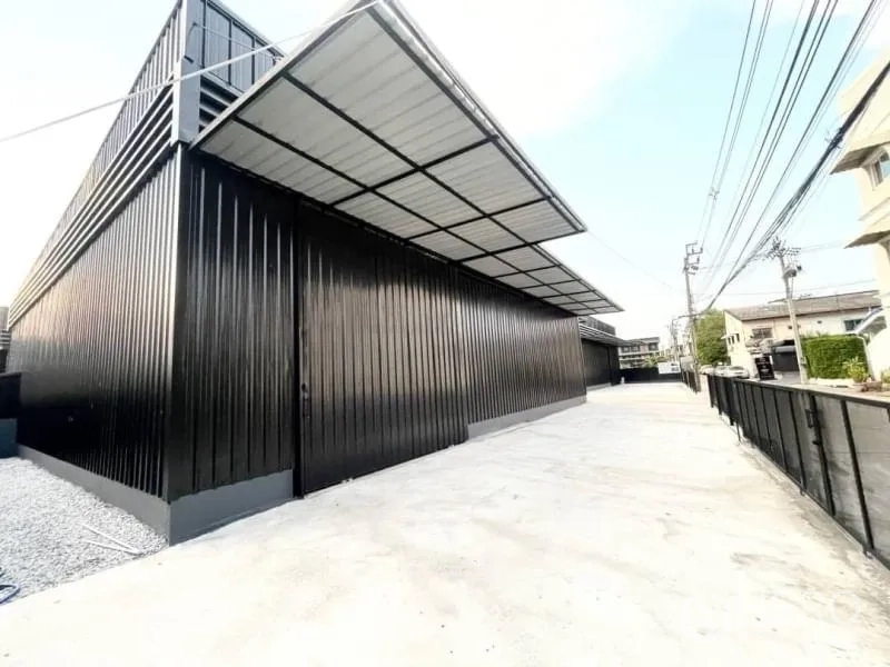 Warehouse for rent in Wang Thonglang, Bangkok - Side view of warehouse with long driveway, covered loading canopy and secure perimeter fence.