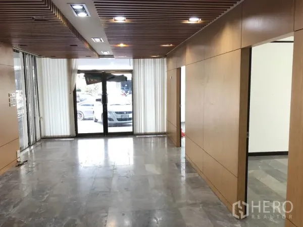 带办公室的家 出租在Huai Khwang, Bangkok - 一层大堂，木质墙面、石材地面、嵌入式照明与玻璃大门。