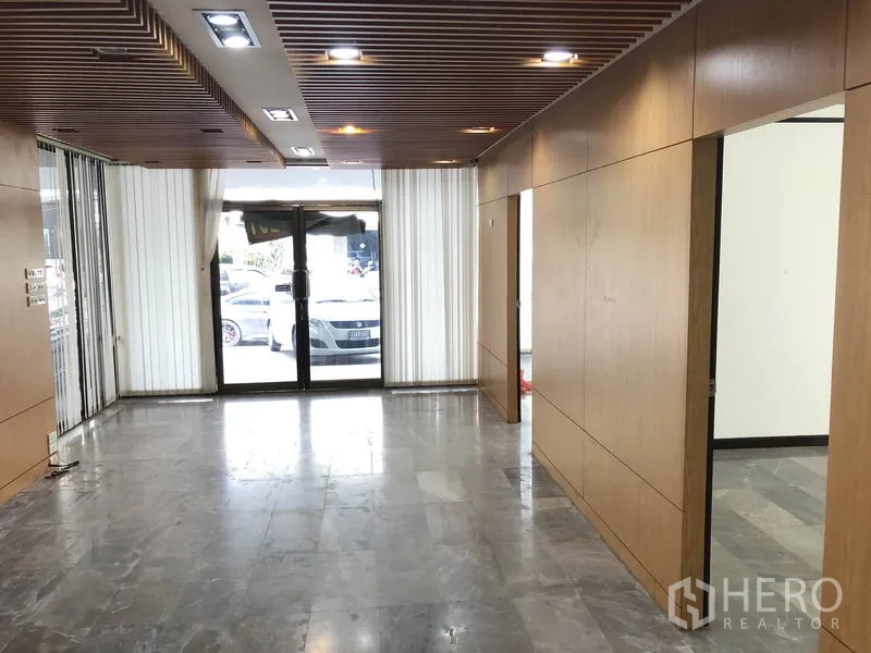 带办公室的家 出租在Huai Khwang, Bangkok - 一层大堂，木质墙面、石材地面、嵌入式照明与玻璃大门。