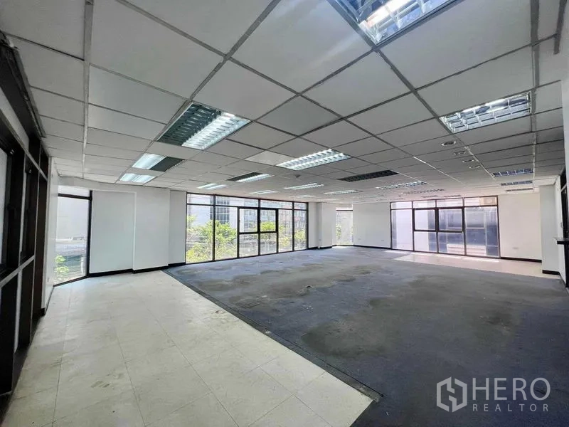 Shophouse for rent in Khlong San, Bangkok - Bright office floor with mixed flooring and panoramic windows over the neighborhood.