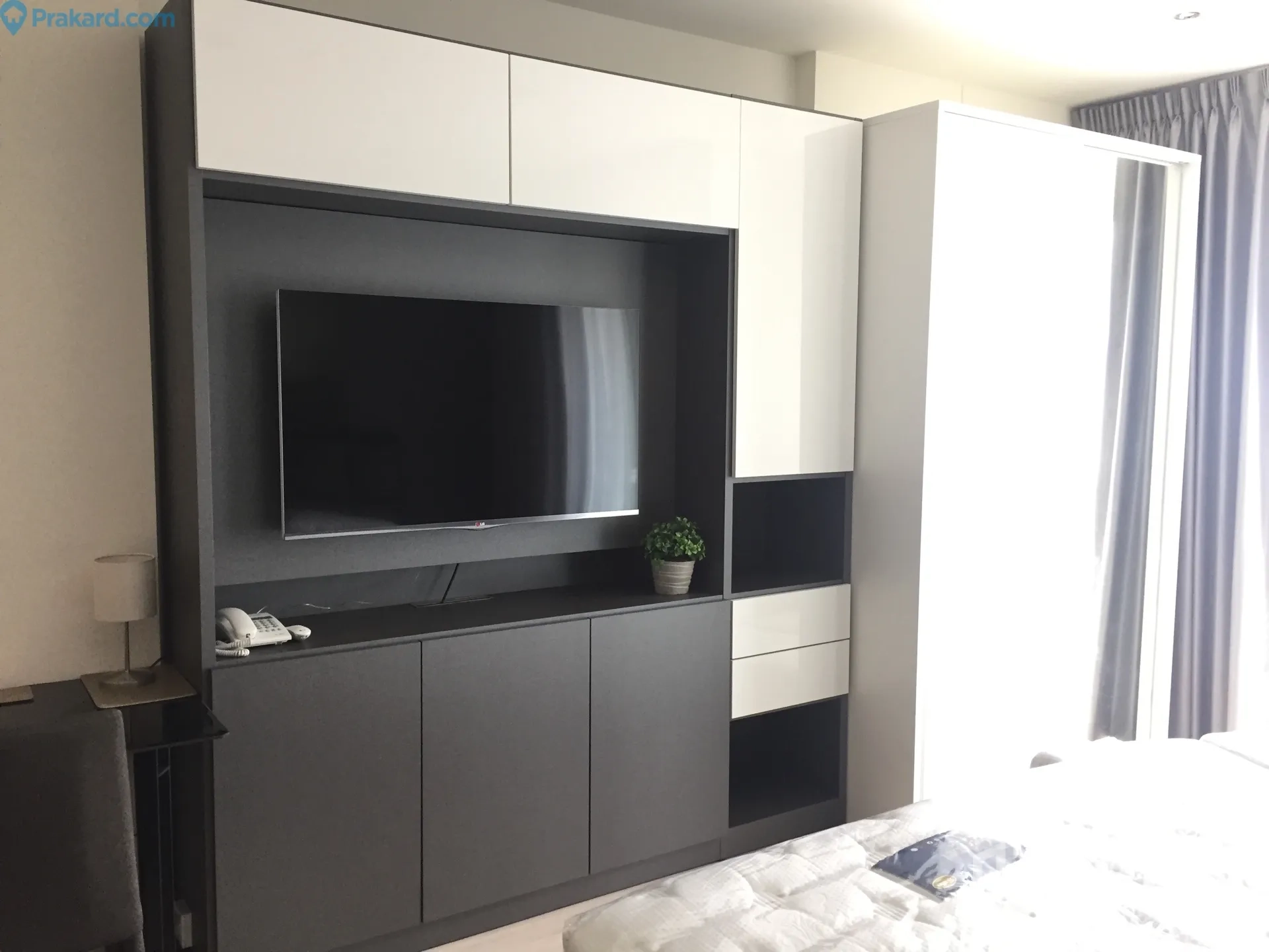 Condominium for rent in Ratchathewi, Bangkok - Built-in media wall with TV, storage cabinets and wardrobe in a bright studio space.