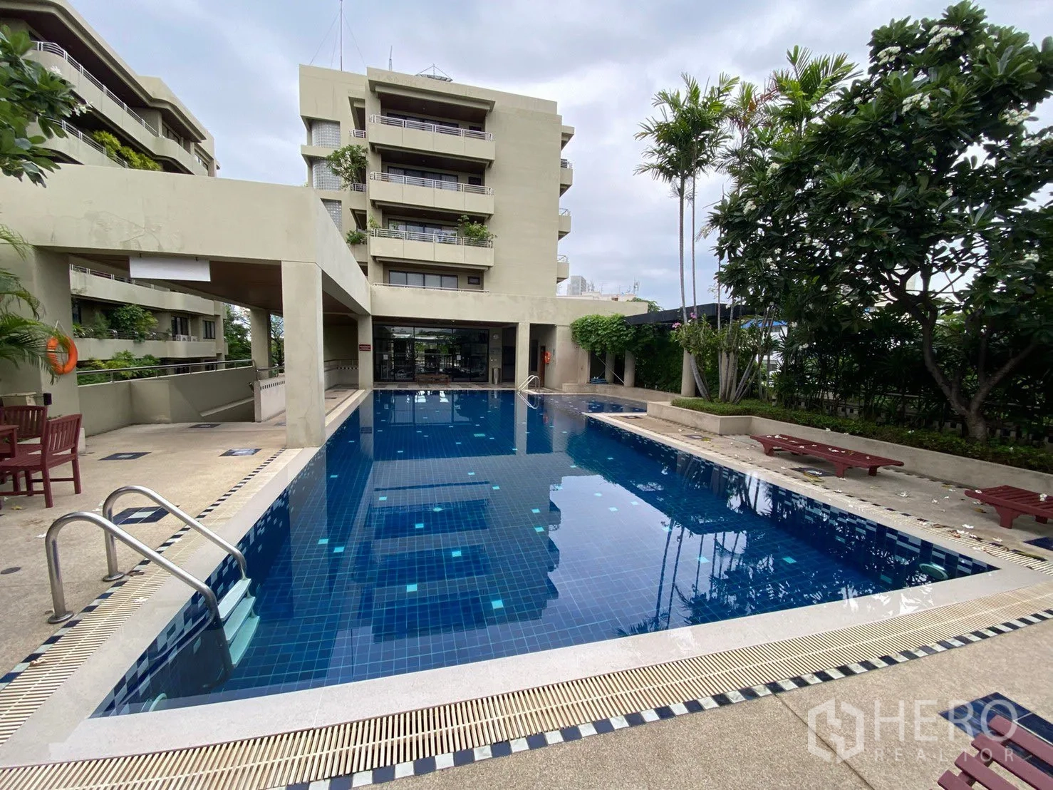 Condominium for rent in Sathon, Bangkok - Outdoor swimming pool surrounded by greenery and low‑rise buildings.