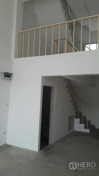 Office Space for sale in Khlong Luang, Pathum Thani - Interior corner with staircase to upper floors, mezzanine railing and a door to a bathroom.