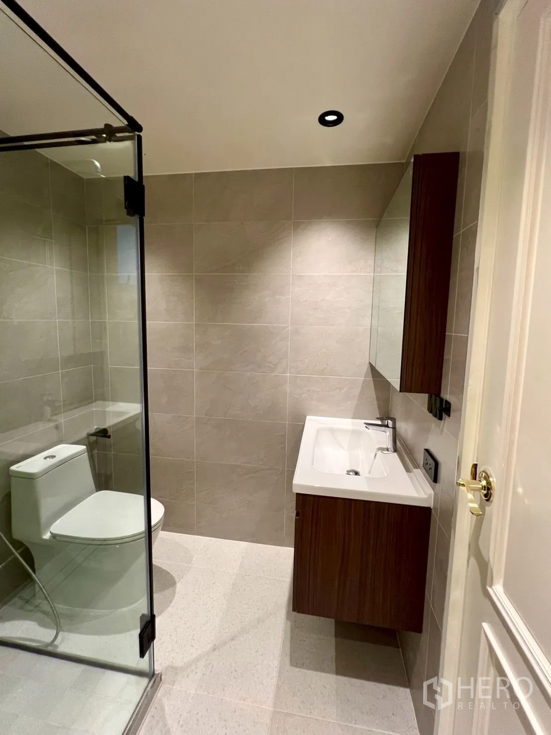 Condominium for sale in Watthana, Bangkok - Tiled bathroom with glass-enclosed shower, vanity, and toilet.