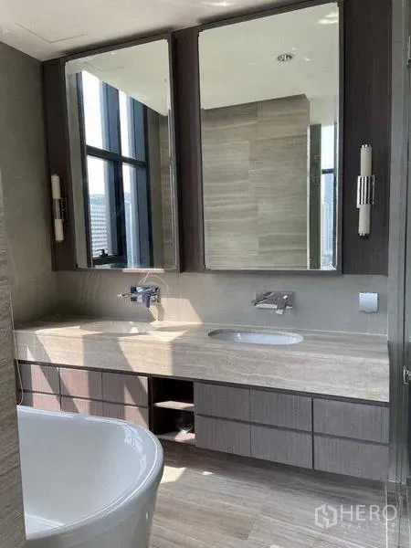 Condominium for sale in Bang Rak, Bangkok - Modern bathroom with long double‑sink vanity, large mirrors and natural light.