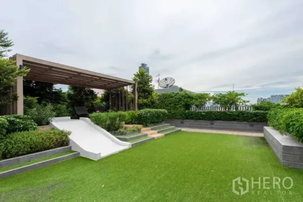 Condominium for rent in Huai Khwang, Bangkok - Rooftop garden with pergola, seating area and manicured lawn.