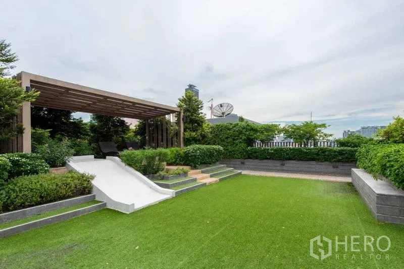 Condominium for rent in Huai Khwang, Bangkok - Rooftop garden with pergola, seating area and manicured lawn.